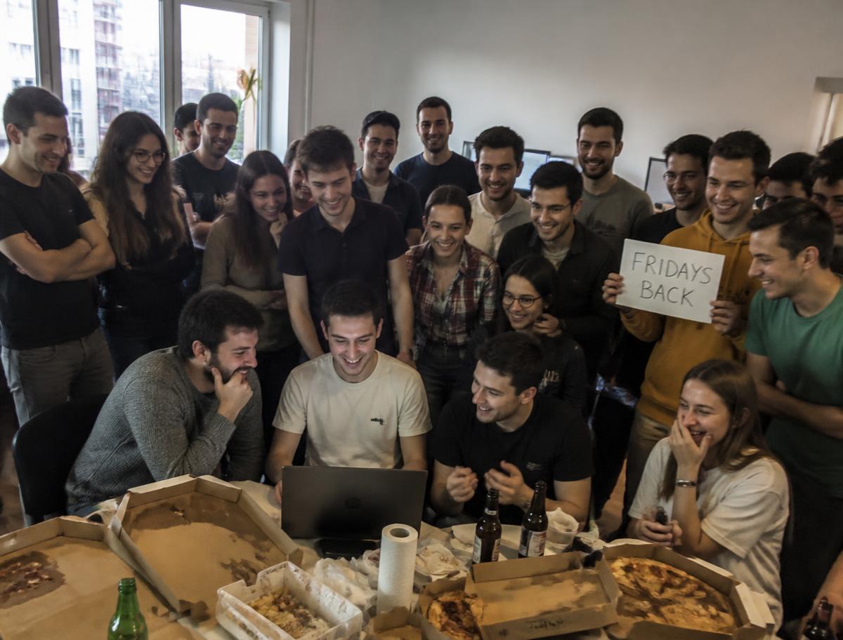 Tudor and his startup team celebrating around a laptop and pizza